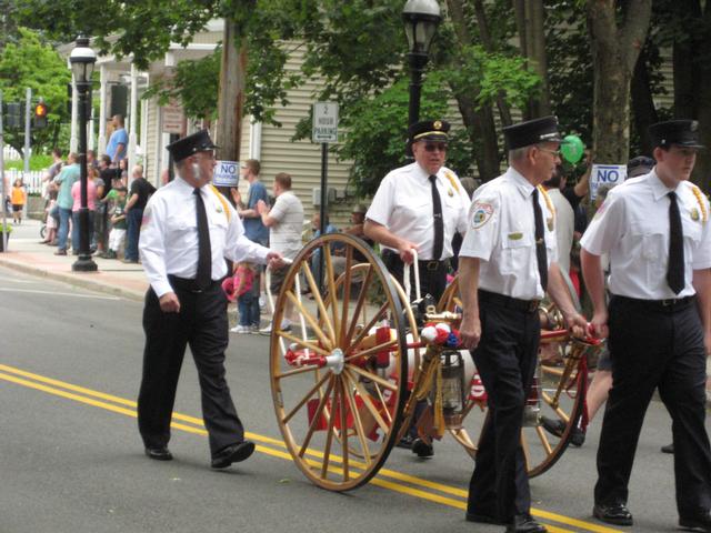 Member's of Harmon Engine assist Ex-Captain Harold Lockwood with his hose cart, part of his &quot;Yesterday's Fires&quot; antiques collection at the 2011 Summerfest Parade.